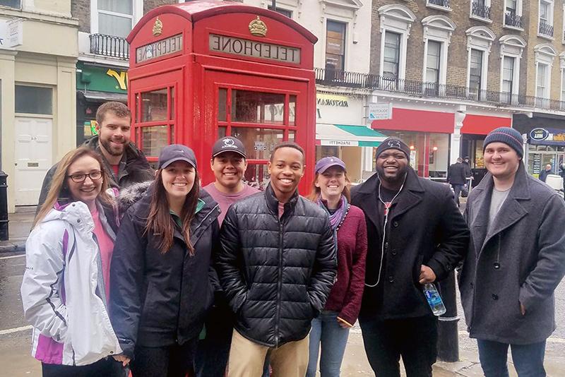 一群学生在伦敦旅行期间站在一个标志性的红色电话亭前